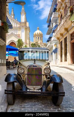 Classic Ford car on a colorful street in Old Havana with the Presidential Palace on the background Stock Photo