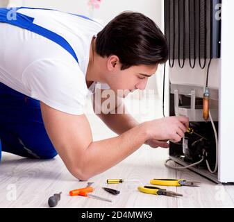 The repairman contractor repairing fridge in diy concept Stock Photo