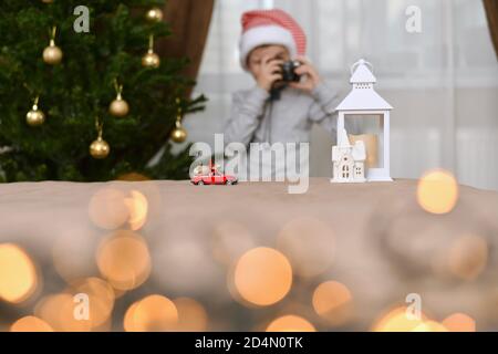 A car with a bag of Christmas gifts goes to the white house of the lantern. A child in a striped cap, with the camera.  Stock Photo