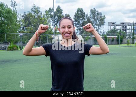 Closeup shot of a young Hispanic woman excited for success with her arms raised Stock Photo