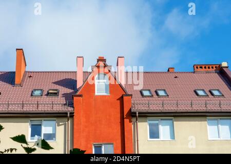 Roof of a residential building with dormers, attic light. Roofing skylights, the bright facade of a building in Europe. Stock Photo