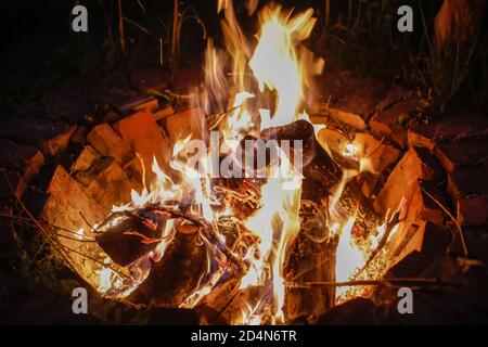 Details of a wood fire in a red brick fireplace dug in the ground Stock Photo