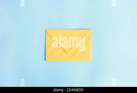 Yellow paper envelope on light blue background. Festive template. Greeting card design. Top view. Stock Photo