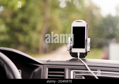 Mobile phone with GPS card in the car. A white smartphone on a stand in the car is used for navigation. Stock Photo