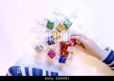 Small colorful gift boxes in child's hands. Christmas and NewYear decorations process. Stock Photo