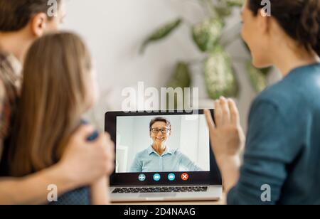 Happy loving family. Father, mother and daughter girl using laptop pc for remote conversation with grandma. Funny mom, dad and lovely child are having Stock Photo