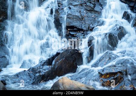 Long exposure waterfall flowing over black rocks Stock Photo