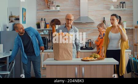 Man returning from market with fruits and bread. Young couple coming from shopping bringing a paper bag with groceries, fresh food, from supermarket at parents home to prepare a family dinner Stock Photo