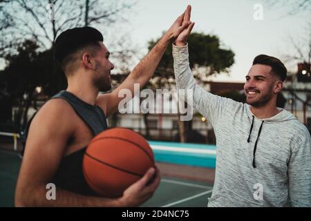 Portrait of two young friends playing basketball and having fun on court outdoors. Sport concept. Stock Photo