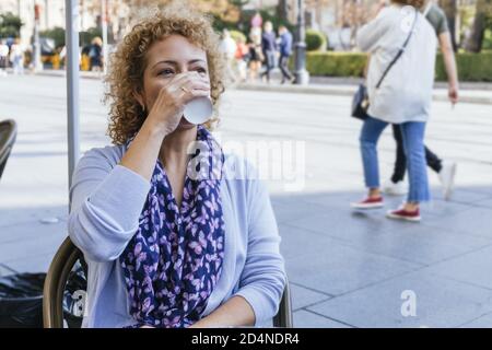 Shallow focus shot of a woman sitting in a cafeteria drinking coffee Stock Photo
