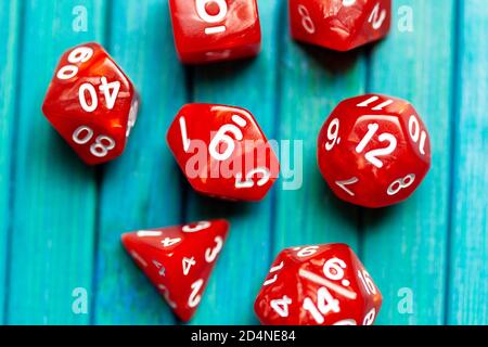Simple RPG polyhedral board game dice set. Lots of red dice on blue wooden background closeup, shot from above, top view. Fun role playing games roll Stock Photo