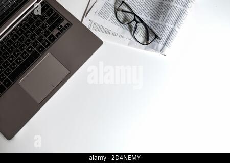 Flatlay home office workspace for isolation. Learning place for homeschooling or workplace for a freelancer. White desk with empty space. Newspaper. Stock Photo