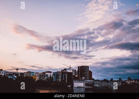 Beautiful sunset in residential area in Lviv, Ukraine. Cityscape with building rooftops and pink clouds on top. Construction site downtown in dusk. Stock Photo