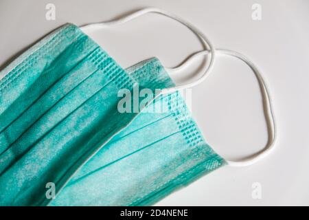Two standard blue face medical masks on a white table. Self protection from virus, bacteria, sickness, corona or flu. Prevention methods in quarantine