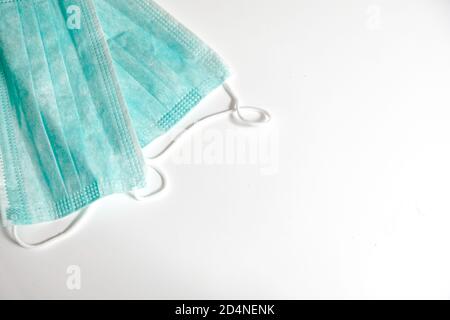 Two standard blue face medical masks on a white table with empty space. Self protection from virus, bacteria, sickness, corona or flu prevention.