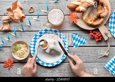 Celebrating Oktoberfest alone. Traditional food and beer, top view on aged wooden table, Stock Photo