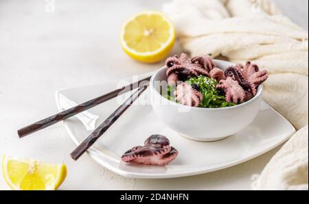 Croped photo of green wakame seaweed salad with sesame seeds and mini octopus served with chopstick at the restaurant Stock Photo