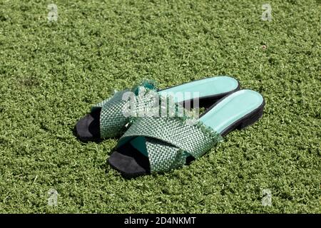Green female fashionable mint colored sandals laying on grass on a sunny day in summer. Relaxing lifestyle, leisure. Stock Photo