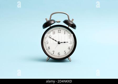 Analog clock front view, isolated on blue background Stock Photo