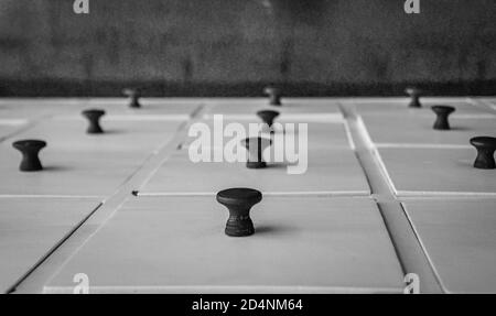 A perspective view of a chest of white wooden drawers with black wooden drawer knobs. Stock Photo