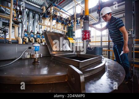 Motor oil modern production plant. Engineer controls processing. Oil heating and mixing. Stock Photo