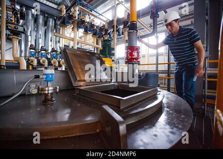 Motor oil modern production plant. Engineer controls processing. Oil heating and mixing. Stock Photo