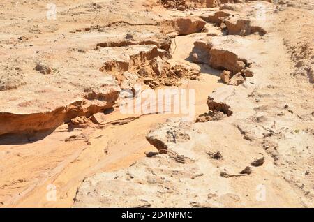 Shattered sand in the ground as a result of heavy torrential rains. Dry cracked soil of the earth due to climate change. Background or texture of the Stock Photo