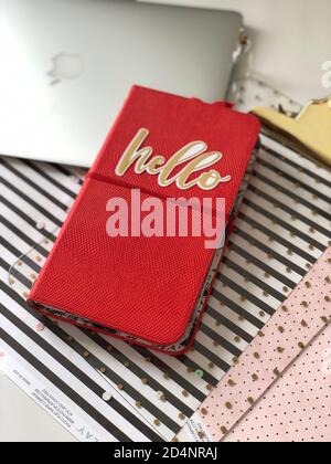 Red notebook with quote Hello, laptop on the table Stock Photo
