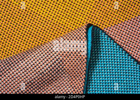 A pile of multi-colored synthetic knitted fabrics of different structures and textures. A stack of colorful fabrics smooth shapes background. Multicol Stock Photo