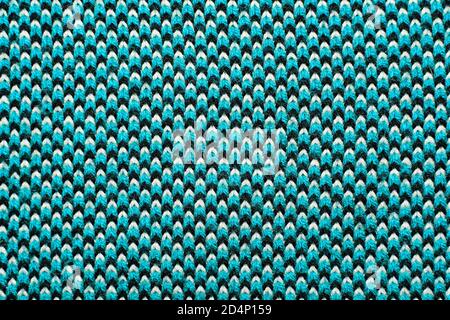 Synthetic knitted fabric with pattern elements of blue, black and white yarns close up. Multicolor patterned knitted fabric texture. Background Stock Photo