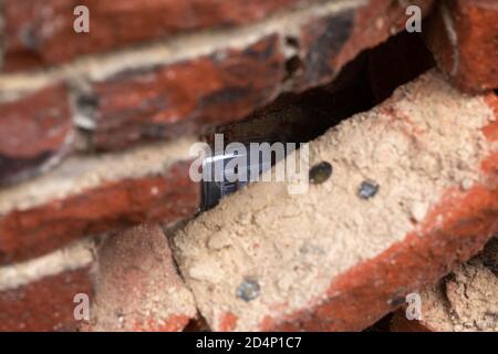 Empty vodka bottles hidden in a breach in old medieval brick wall. Gniezno, Poland. Stock Photo