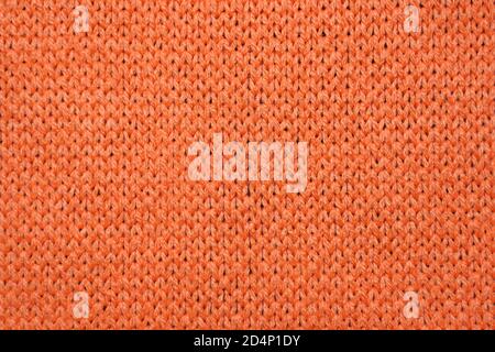 Red synthetic knitted fabric close up. Knitted fabric texture background Stock Photo