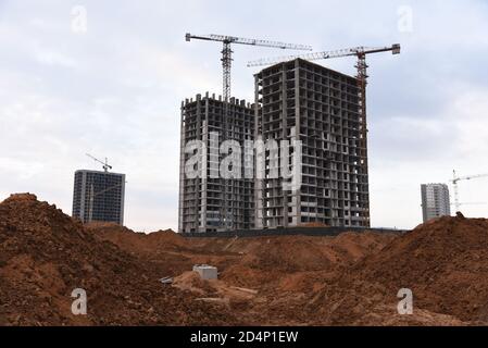Tower cranes constructing a new residential build. Pouring concrete into formwork of building at construction site. Laying or replacement of undergrou Stock Photo