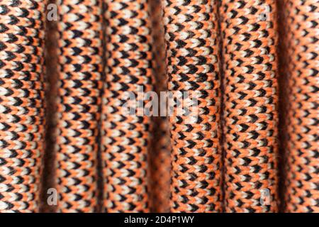 Folded synthetic knitted fabric with pattern elements of red, black and white yarns close up. Multicolor patterned knitted fabric texture. Background Stock Photo