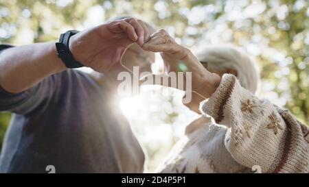 Lovely older retired couple making heart with their hands and looking at each other. Selective focus. High quality photo Stock Photo