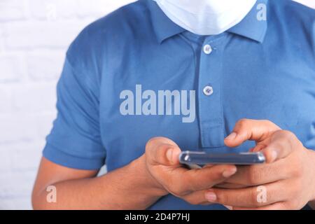 young man with face mask using smart phone indoor  Stock Photo
