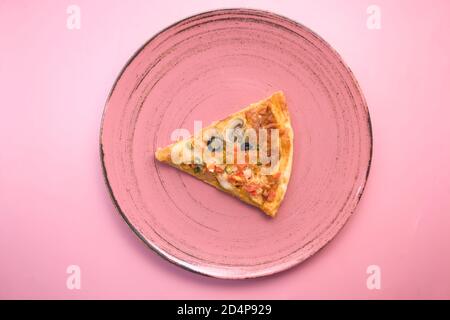 Slice of vegetable pizza on a plate on pink table. Stock Photo