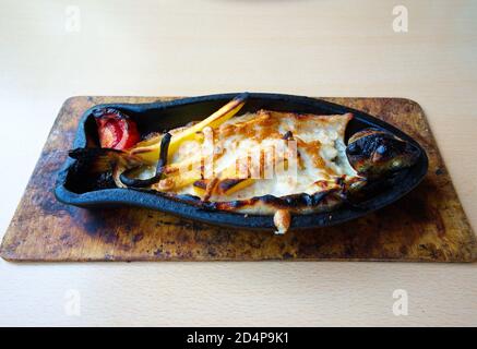 Trout in clay soil pot. baked in oven with cheddar, potatoes and vegetables. presentation with mixed vegetable salad Stock Photo