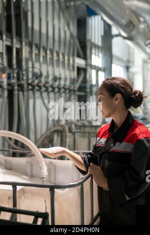 Young female factory worker or quality control manager holding pile of pellets Stock Photo
