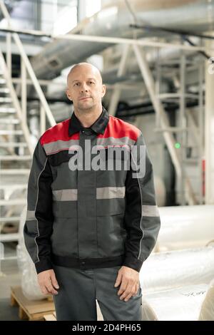 Bald mature male engineer in workwear standing inside polymer processing factory Stock Photo