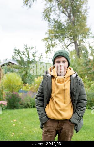 Handsome and adorable schoolboy in beanie, hoodie, pants and warm jacket Stock Photo