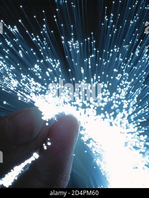 Fibre optics handheld between forefinger and thumb. Stock Photo