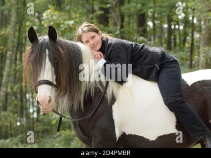 Teenage girl bareback riding Gypsy Vanner Horse mare on wooded trail Stock Photo