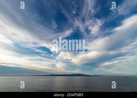 In the distance a formation of clouds over water and a small island. Stock Photo