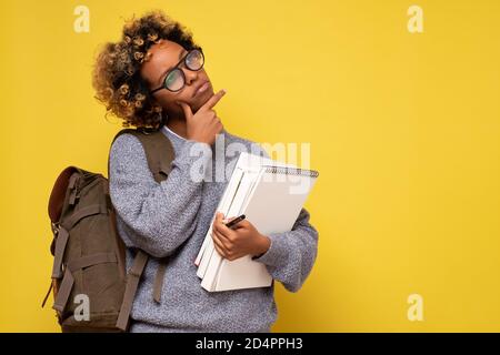 Pretty african woman with curly hair and glasses looking up with thoughtful look. Stock Photo