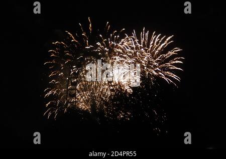 A ferris wheel in front of golden fireworks, lighting up the night Stock Photo