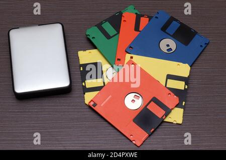 Cilorful retro floppy disks and modern external hard drive on wooden table Stock Photo