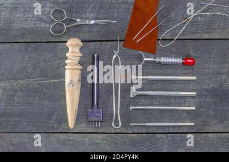 Flat set of leather tool kit for beginners. Leather instrument set on wood background. Leather edge burnisher. Stock Photo