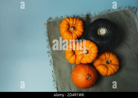 Top view decorative pumpkins on green napkin. Autumn harvest composition on trendy earth tones color background. Autumn, fall, thanksgiving, halloween Stock Photo