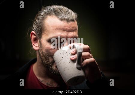 Young man enjoys a tea or coffee with his eyes closed Stock Photo